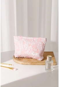 Detailed view of pink floral jacquard makeup bag with fabric brand label and zipper