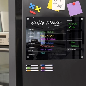 Detailed view of clear acrylic weekly planner on black fridge with six colorful markers