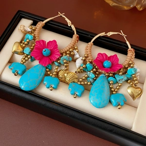 Detail of bohemian earrings with turquoise beads, pink fabric flowers and gold pendants