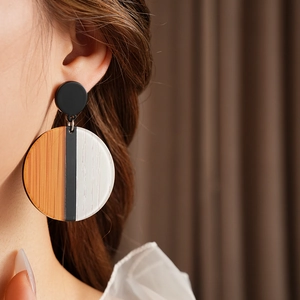 Gros plan de boucles d'oreilles rondes géométriques avec grain de bois et résine colorée