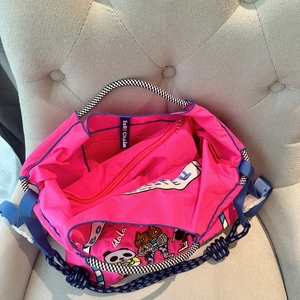 Close-up of pink nylon inner bag with detailed cat embroidery and blue strap