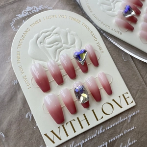 Detail of pink gradient press-on nails with large iridescent rhinestones on a white display card