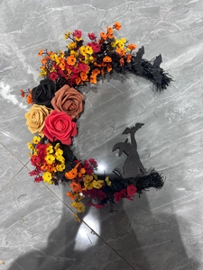 Close-up of crescent moon cat wreath with black bats and vibrant autumn flowers