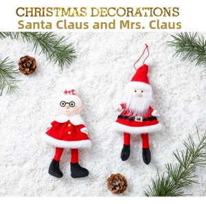 Close-up of plush Santa Claus and Mrs. Claus ornaments on artificial snow background
