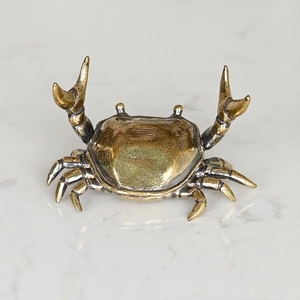 Macro detail of the vintage brass crab figurine showing textured oxidized metal finish