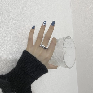 Polished silver wave ring on finger holding a glass for minimalist lifestyle styling