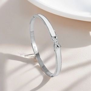 Detailed close-up of silver stainless steel bangle featuring X-shaped cubic zirconia inlay