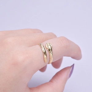 Detailed view of adjustable golden snake ring with scales on hand with purple background
