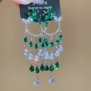 Détail de boucles d'oreilles pampilles en argent avec cristaux verts et blancs