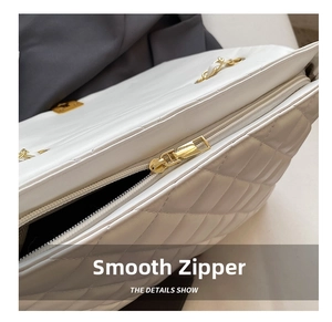 Detail showing high-quality golden smooth zipper on a white quilted chain crossbody bag