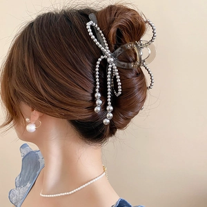 Silver bow hair claw clip with metallic faux pearls shown on a woman's hair in a back view