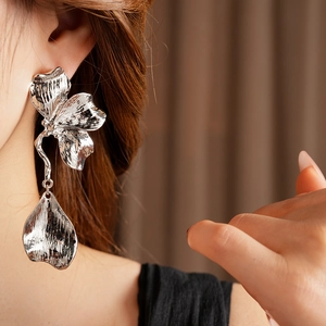 Close-up of silver metal flower earrings with hammered texture on a model