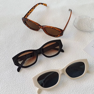 Flat lay of cat-eye sunglasses in leopard, black, and beige colors on textured background