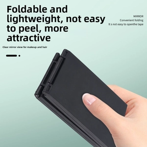 Detailed close-up of a portable black four-way folding makeup mirror held in one hand