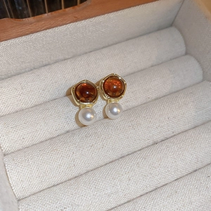 Gros plan détaillé de boucles d'oreilles dorées avec ambre et perle dans une boîte à bijoux