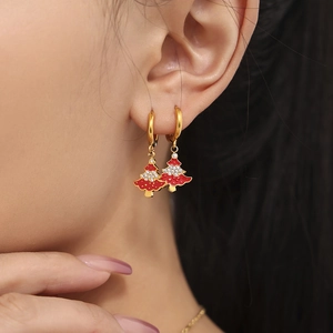 Gold Christmas tree hoop earrings with red enamel and rhinestones on female model