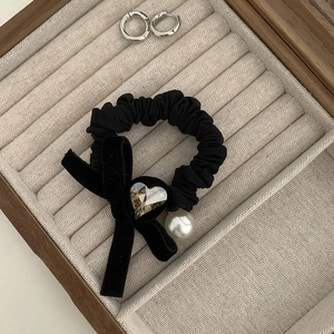 Detail of black velvet bow hair tie featuring a heart crystal and elegant pearl pendant