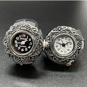 Close-up of black and white quartz ring watches with silver metal cases on dark background