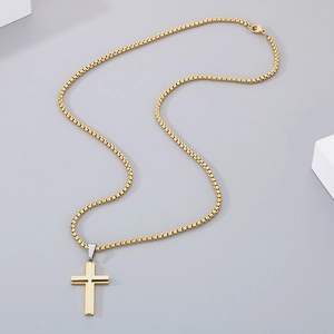 Macro detail of golden cross pendant with silver accent on a box chain necklace