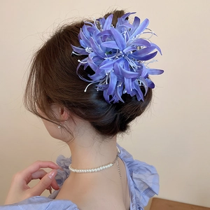 Détail de la pince à cheveux fleur violette avec gland de perles sur tresse élégante