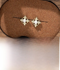 Detail of coffee gold iris stud earrings in titanium steel with zircon inlay