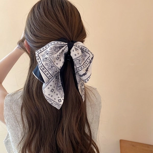 Detail of a large black and white bow hair clip worn by a model in a ponytail hairstyle
