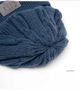 Dettaglio del berretto in maglia a trecce blu scuro con trama spessa e etichetta city