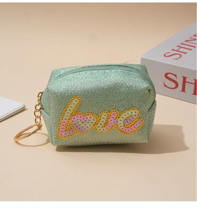 Macro shot of mint green glitter coin purse with colorful Love sequin embroidery