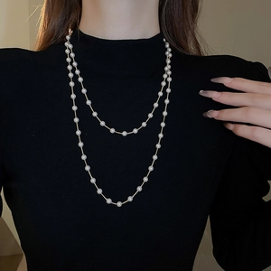 Détail d'un collier de perles superposées avec chaîne dorée sur col roulé noir élégant
