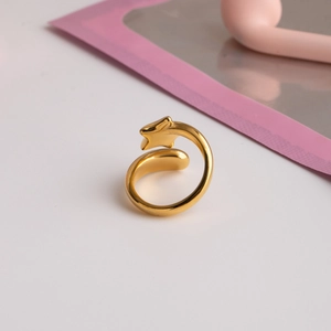 Gros plan d'une bague ouverte dorée avec étoile et goutte d'eau et éclat métallique