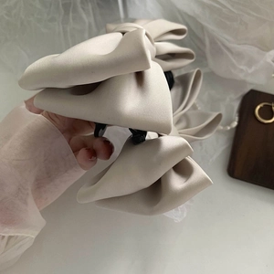 Close-up of beige silk bow hair claw clip with elegant triple-layer satin ribbons