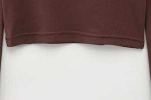 Detailed close-up of brown knit t-shirt hem featuring fine texture and neat stitching