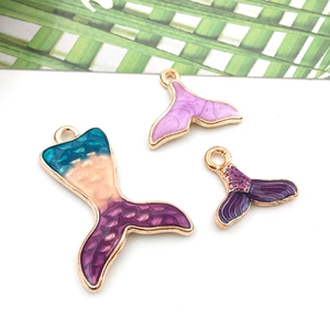 Detail of purple enamel mermaid tail charms for DIY jewelry making on white background