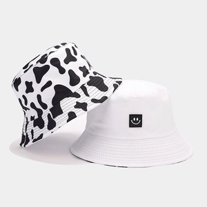 Detail of cow print and white smiley face reversible bucket hats made of cotton canvas