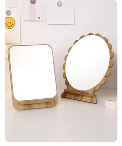 Detail of a desktop wooden vanity mirror with a wave-shaped frame on a bright white table