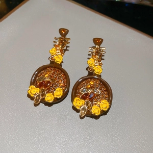 Dettaglio macro di orecchini a forma di pipa con fiori di smalto e cristalli