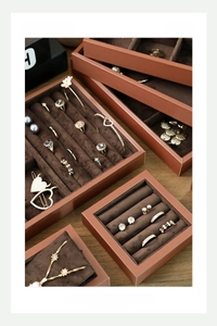 Detailed stack of brown leather jewelry trays with velvet lining and ring slots