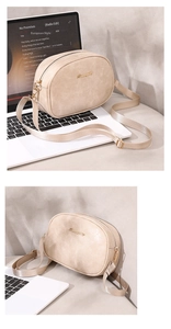 Close-up of beige oil wax leather crossbody bag with golden logo and fabric strap