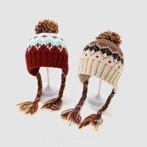 Detailed knit texture of children's warm earflap hats with pom-poms and braided tassels