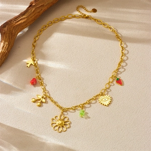 Gold chain necklace with sunflower and fruit charms on a natural sandy background