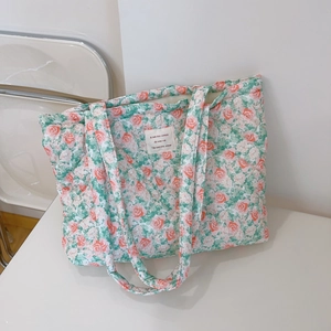 Detail of floral quilted tote bag with a white woven label and soft cotton texture