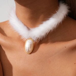 Détail d'un collier ras de cou en fourrure blanche avec perle ovale et bordure dorée
