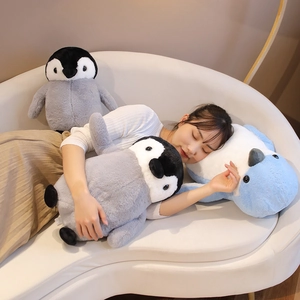 Close-up of soft plush penguin pillows on a sofa showing large size and fluffy texture