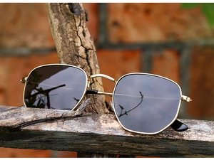 Detail of polarized sunglasses with gold metal frame and dark lenses on wood