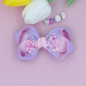 Detail of purple and pink ribbon bow clip with heart sequins and transparent heart charms