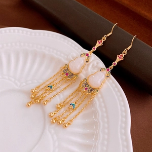Detail of gold-plated gourd earrings with jade-like texture and long tassel fringes