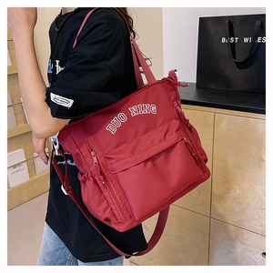 Close-up of red high-capacity nylon tote bag with multi-pocket design on model