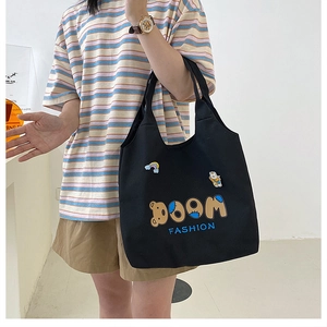 Detail einer großen schwarzen Canvas-Tasche mit DOOM FASHION Text und Bären-Aufnäher