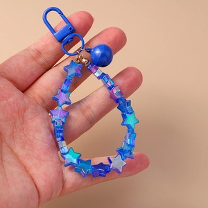 Blue gradient star beaded keychain with bell and lobster clasp on a beige background