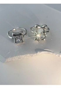 Detail view of two silver open rings with square gemstones on white stone background